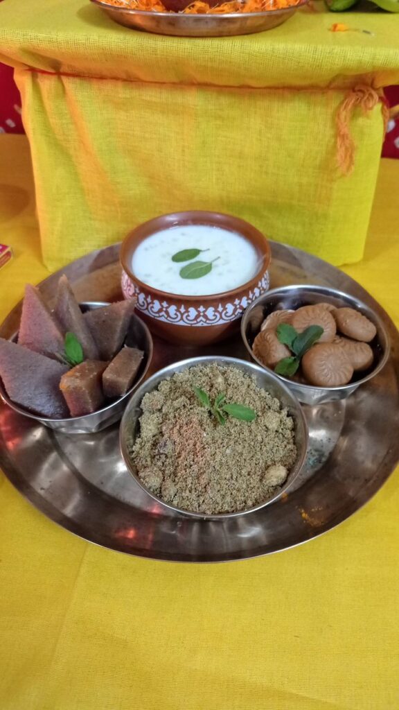 A traditional offering plate prepared for Krishna Janmashtami 2024, featuring sacred prasad items like panchamrit, sweets, and powdered offerings, all beautifully arranged on a silver platter with tulsi leaves for the rituals dedicated to Lord Krishna.